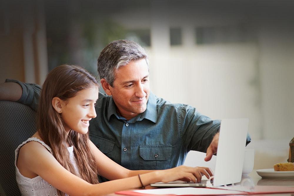 Young girl with learning partner taking an online class smiling at the camera wearing at New Mexico Connections Academy. 